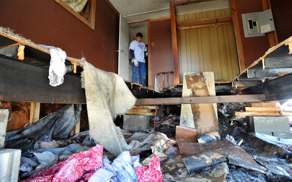 Starting over: Charlie Landry, 20, rummages through the bedroom after a fire destroyed his newly rented mobile home in Anson on Saturday. Landry and his girlfriend, Skyla Murray, were moving on Saturday when a frayed wire in the dryer sparked the fire.