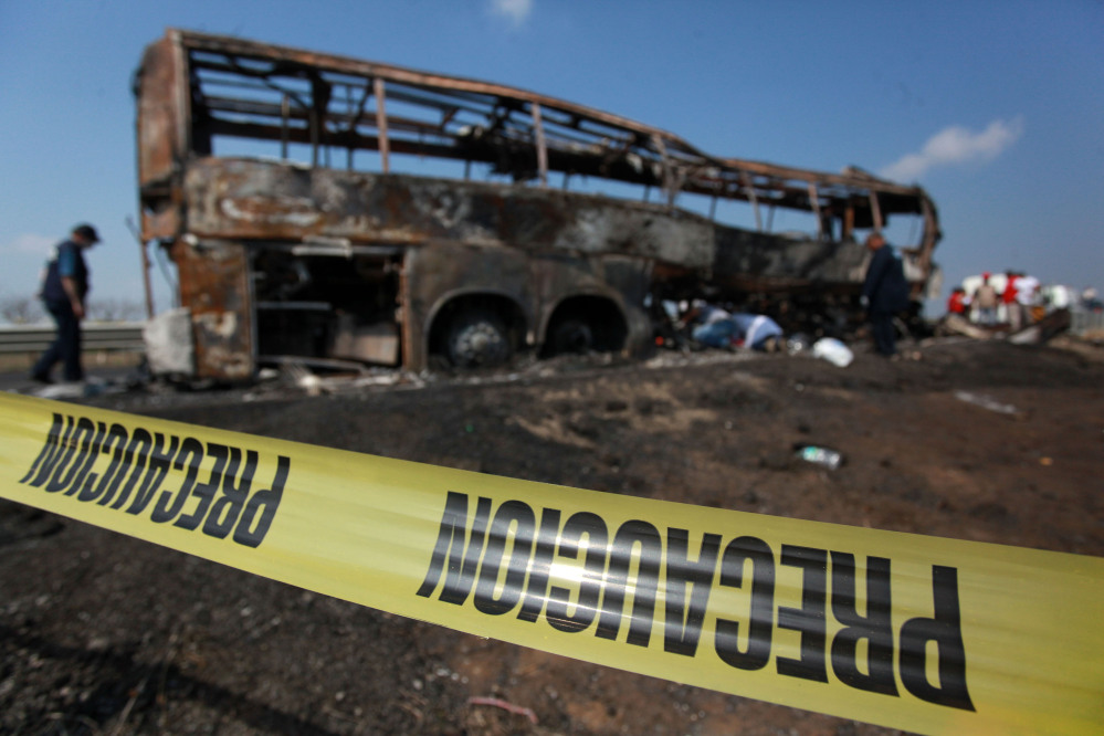 Caution tape creates a perimeter around a passenger bus that slammed into a broken-down truck and burst into flames near the town of Ciudad Isla in the Gulf state of Veracruz, Mexico, on Sunday.