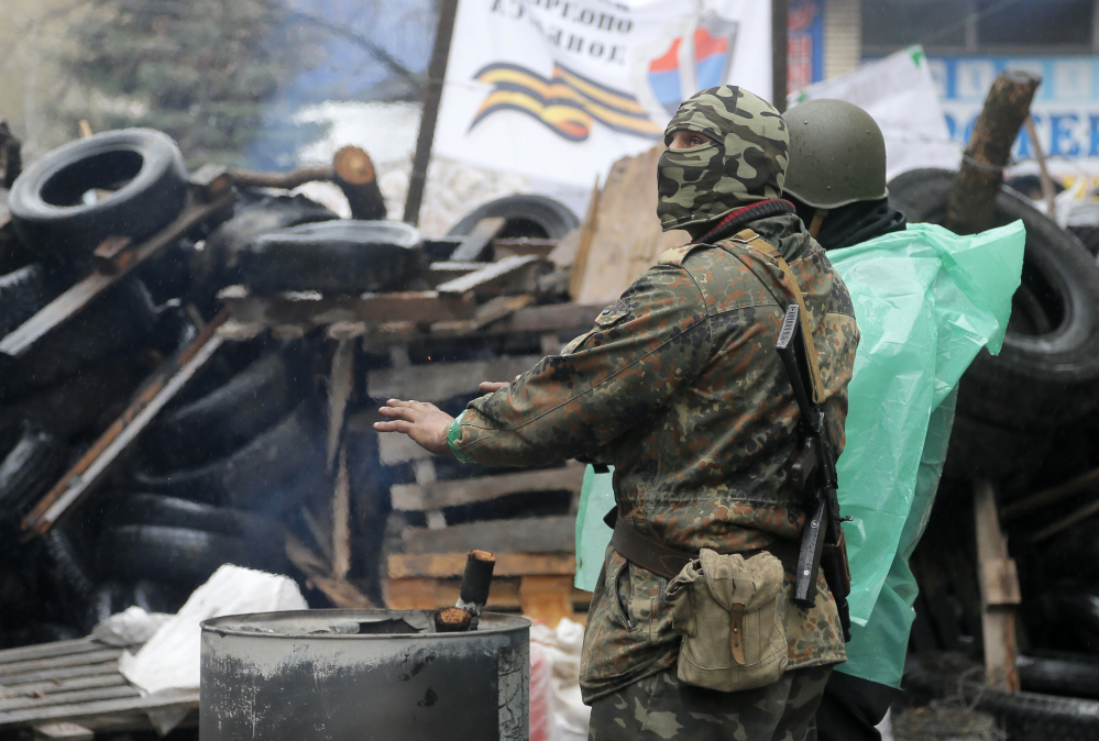A pro-Russian gunman warms himself next to a bonfire as guards a seized police station in the eastern Ukrainian town of Slovyansk on Sunday. Ukrainian special forces exchanged gunfire with a pro-Russia militia in the eastern city Sunday, with at least one security officer killed and five others wounded.