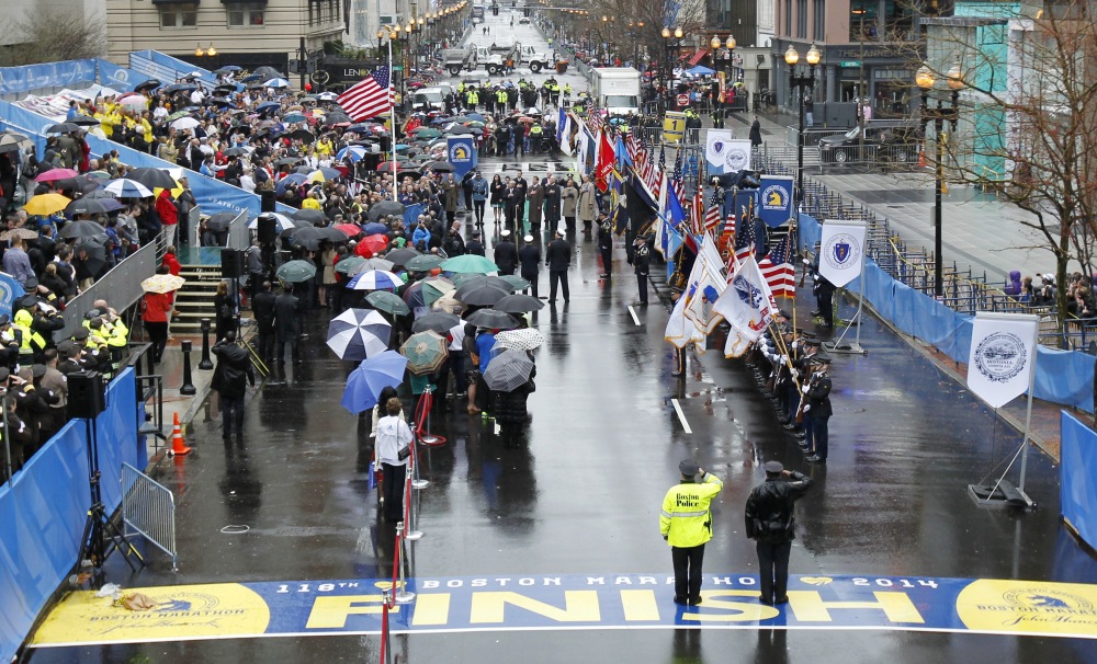 Survivors, officials, first responders and guests pause as the flag is raised at the finish line during a tribute in honor of the one year anniversary of the Boston Marathon bombings on Tuesday in Boston.