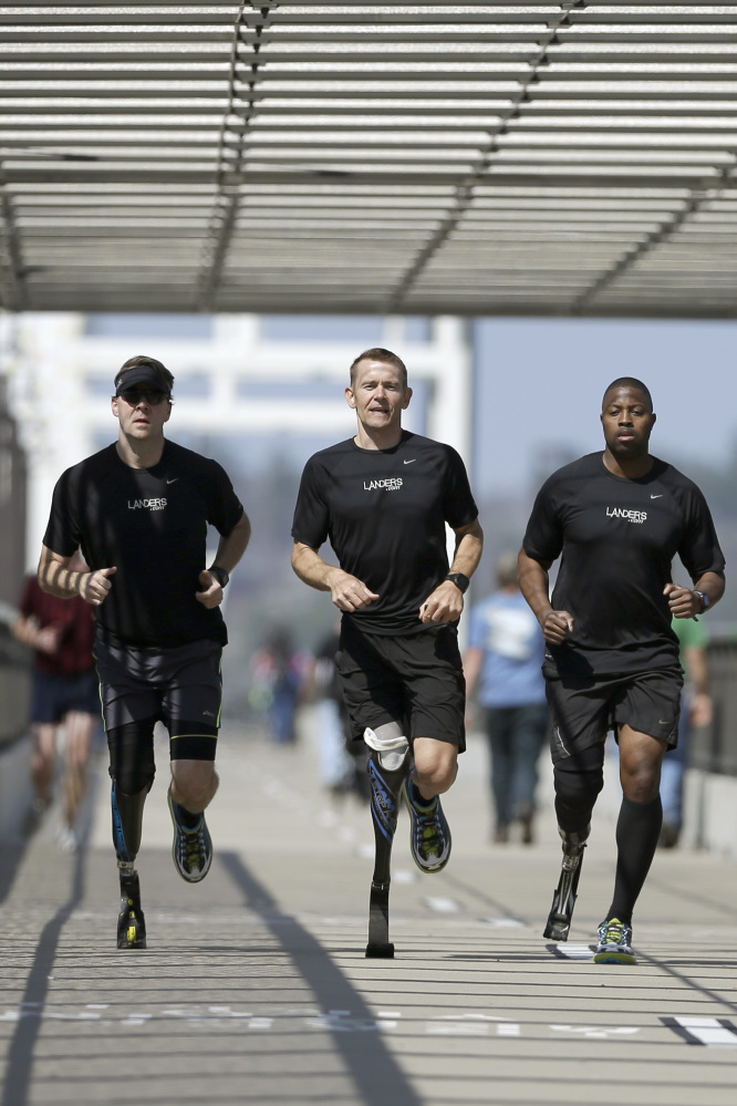 Amputee marathon runners Chris Madison, left, Jeff Glasbrenner, center, and Andre Slay train on a footbridge in Little Rock, Ark.