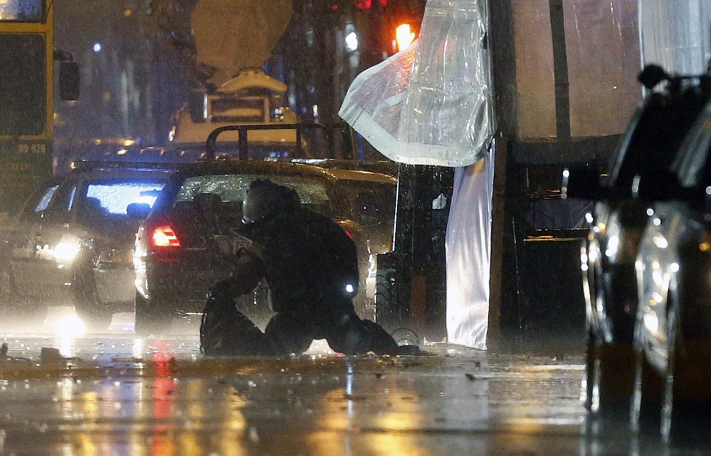A member of the bomb squad inspects an object found at the finish line of the Boston Marathon Tuesday. Police later blew up the two unattended backpacks and took Kevin “Kayvon” Edson, 25, into custody in connection with one of them.