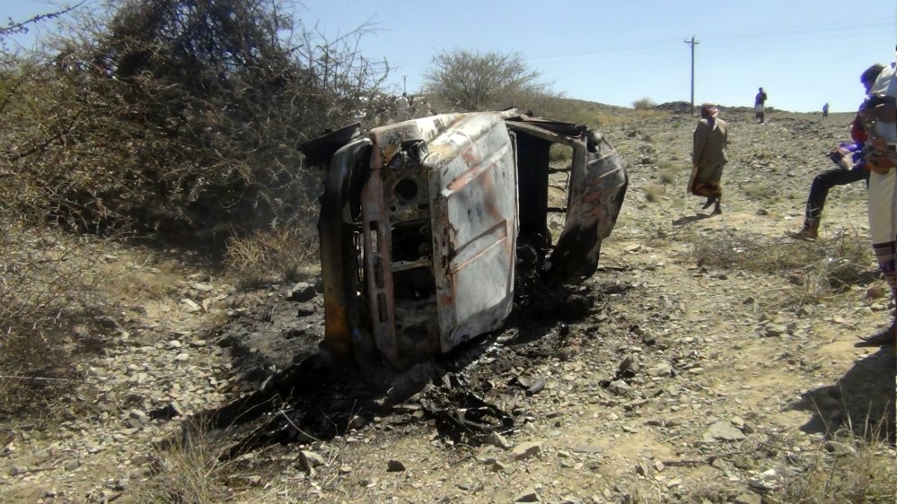 People gather near a destroyed car that was carrying militants in the Sawmaa area of al-Bayda province, Yemen, Saturday.