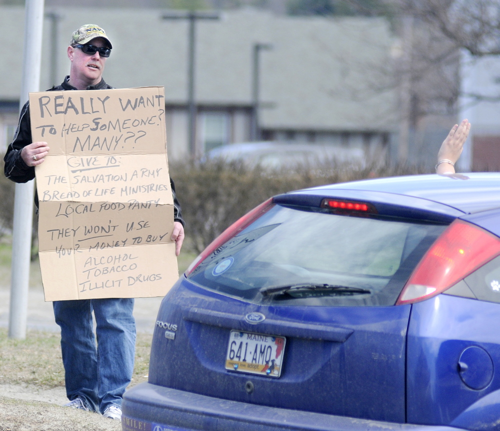 MAKING A POINT: Augusta Police Chief Robert Gregoire speaks with a driver Friday while carrying a sign that discourages drivers from giving money to panhandlers who frequently congregate on the island at the intersection of Western Avenue and Memorial Circle in Augusta. Arriving at 9 a.m. on a day off from his duties, Gregoire said he wanted to encourage generous drivers to make contributions to area homeless shelters and food kitchens instead of directly to people who say they are homeless.
