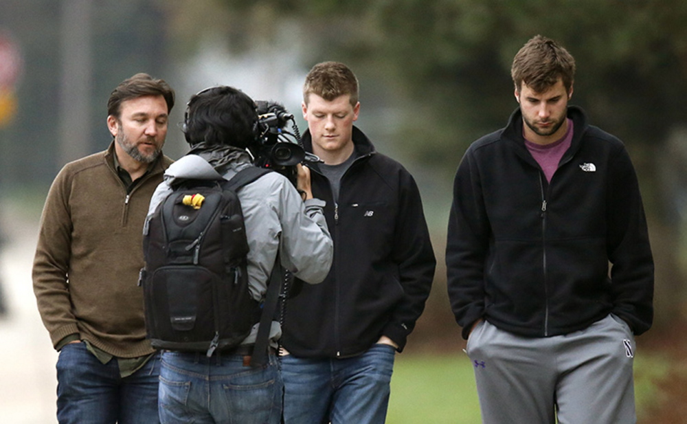 Northwestern football players Chris Gradone, center, and Zach Oliver, are the focus of media attention as they walk to McGaw Hall where voting is taking place on the student athlete union question.