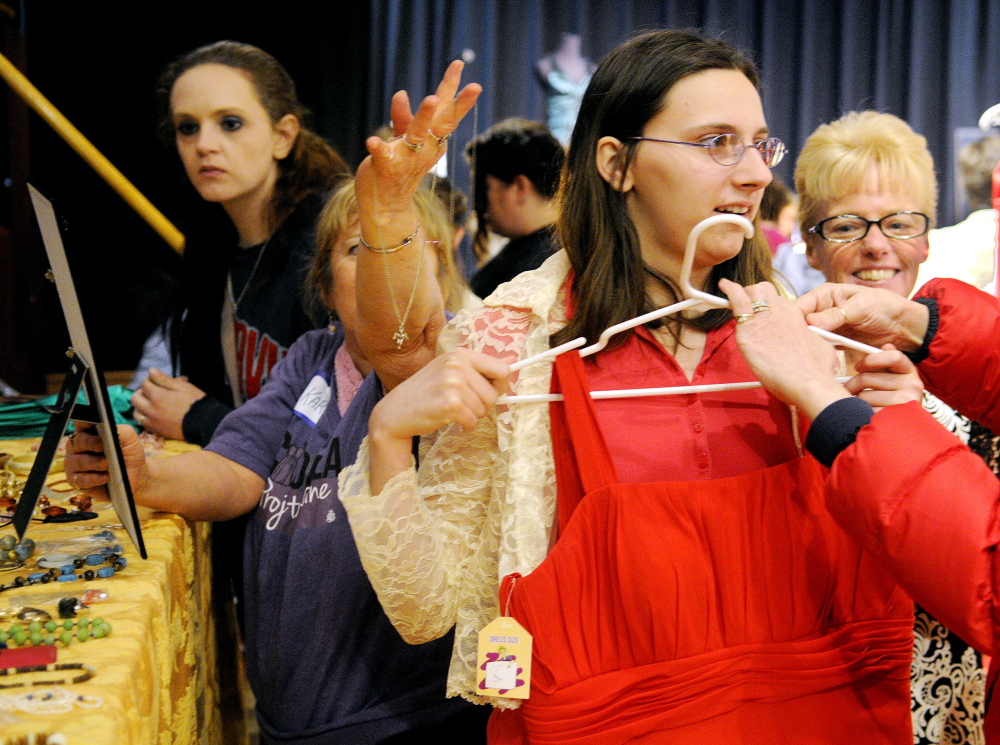 Fully equipped: Brandy Foster, 17, of Unity, gets attired with jewelry and a prom dress Saturday at Johnson Hall in Gardiner. More than 100 teenage girls selected donated dresses, shoes and jewelry as part of the Cinderella Project.