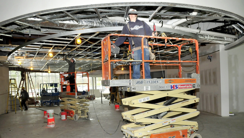 GOING UP: Workers inside the lobby and library section of the new Alfond Academic Center under construction at Thomas College in Waterville.