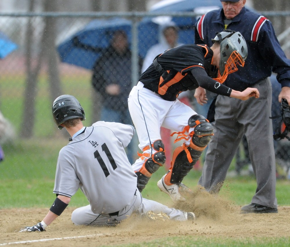 Staff photo by Michael G. Seamans Lincoln Academy's Devin Scheter, 11, scores as the ball goes by Winslow catcher Bobby Chenard, 4, in Winslow on Friday. Lincoln defeated Winslow 8-0.