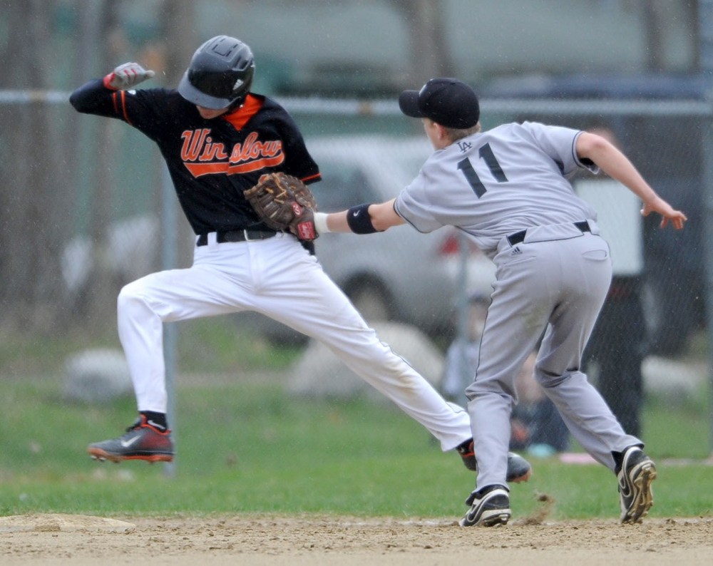 Staff photo by Michael G. Seamans Lincoln Academy first baseman Devin Scheter, 11, right, tags out Winslow High School's Tayler Roy, 11, in Winslow on Friday. Lincoln defeated Winslow 8-0.