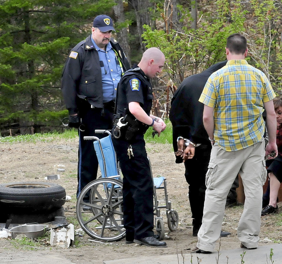 BUST: Three Skowhegan police officers including officer Ryan Dinsmore, center, place a man in handcuffs outside a home at 39 North School St. on Wednesday, following a raid by Skowhegan, Somerset County Sheriffs Office, Maine State Police and officers with the Maine Drug Enforcement Agency.