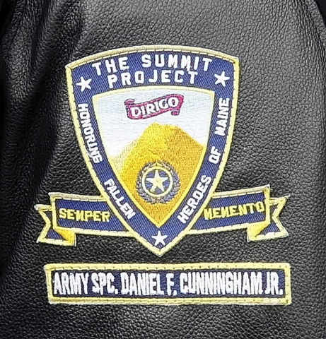 SIGN OF THE CAUSE: David Boyd and his wife, Toby Boyd, wear patches memorializing Army Sgt. Daniel Cunningham next to their The Summit Project patches.