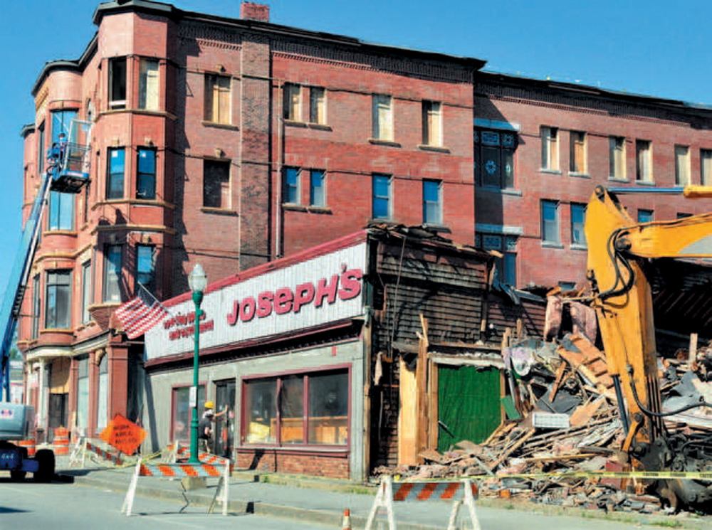 Staff file photo by David Leaming UP AND DOWN: Crews tear down the former Joseph’s Sporting Goods store as workers restore the Gerald Hotel on Main Street in Fairfield in June 2013. The Gerald renovation is part of an ongoing effort to revitalize the blighted downtown.