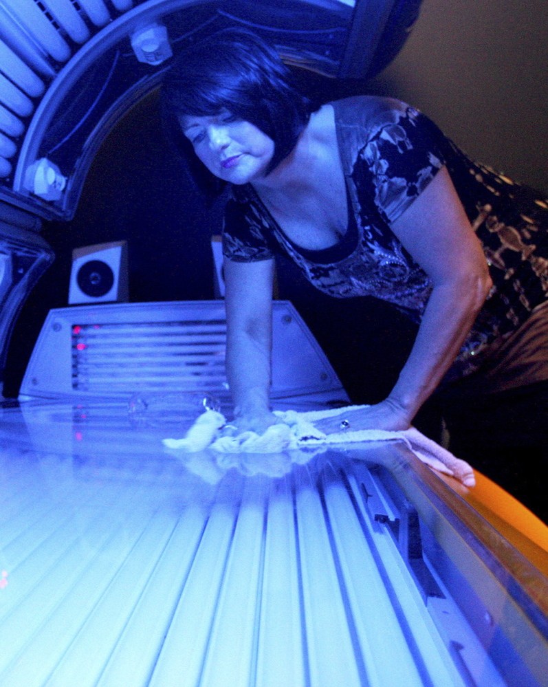 Teresa Lynch, owner of Dynamic Tanning in DeKalb, Ill., wipes down a tanning bed. Tanning beds and sun lamps will carry warnings that they should not be used by anyone under age 18.