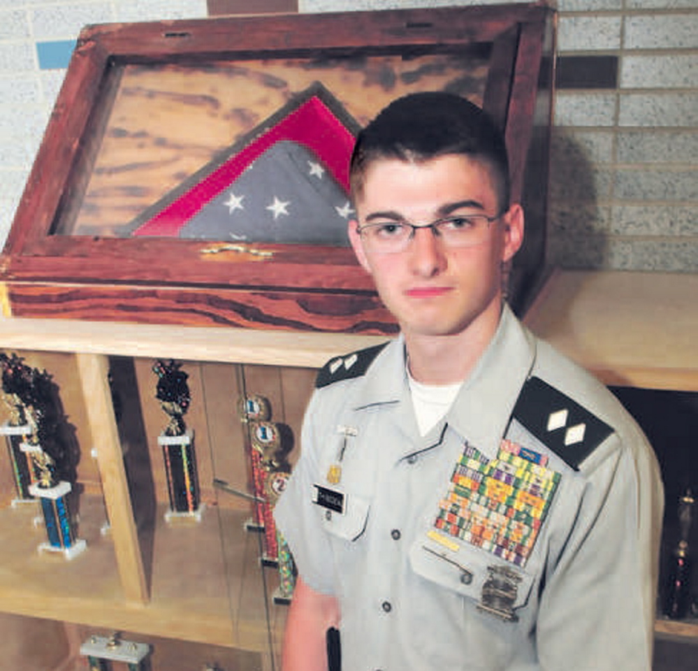 Staff photo by David Leaming RECOGNITION: Nokomis Regional High School student Felix Thibodeau who is also a Cadet Lt. Col. of the Nokomis JROTC Battalion, stands beside an organization trophy case at the school in Newport on Monday, June 2, 2014. Thibodeau is being recognized for his efforts to raise money and awareness for the Togus Veterans Association Homeless Veterans Department.