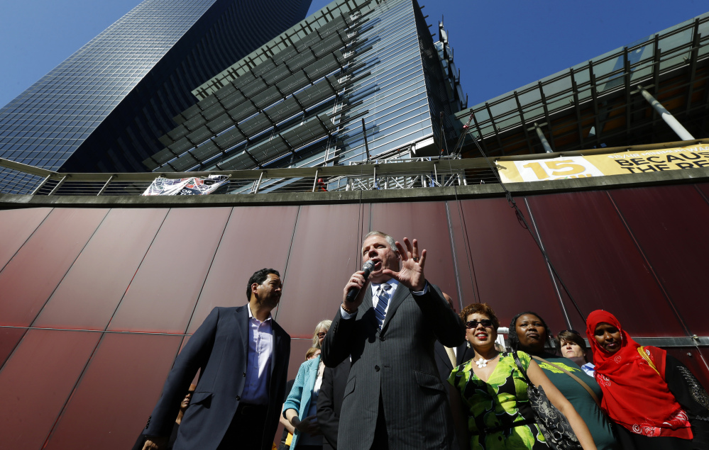 Seattle Mayor Ed Murray, center, speaks Monday at a rally outside Seattle City Hall after the City Council passed a $15 minimum wage measure.