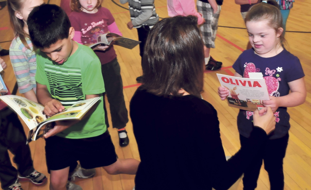 Staff photo by David Leaming
WELL READ: Winslow Elementary school teacher Jen Morneault handed out books to students Tucker Pomeleau, left, and Kylie McCafferty as part of the Read Across America program on Thursday.