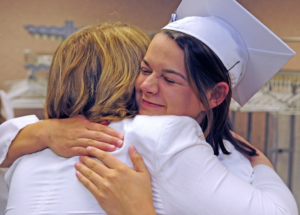 Staff Photo by Joe Phelan GRADUATION: Guidance counselor Betsy Benner, left, and senior Hannah Bridges hug before Erskine Academy graduation on Friday at the Augusta Civic Center.