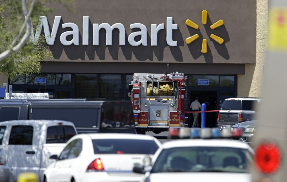 The Associated Press Police and firefighters appear on the scene of a shooting at a Walmart, Sunday in Las Vegas. Police say two suspects shot two officers at a Las Vegas pizza parlor before fatally shooting a person and turning the guns on themselves at a nearby Walmart.