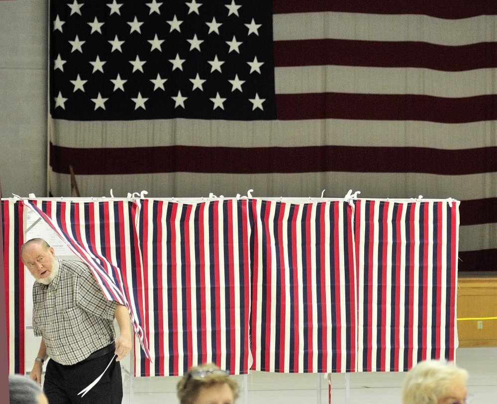 Staff photo by Joe Phelan Decision time: Davy Crockett emerges from a voting booth in front of a large American flag around 9:20 a.m. on Tuesday in the Augusta Armory.