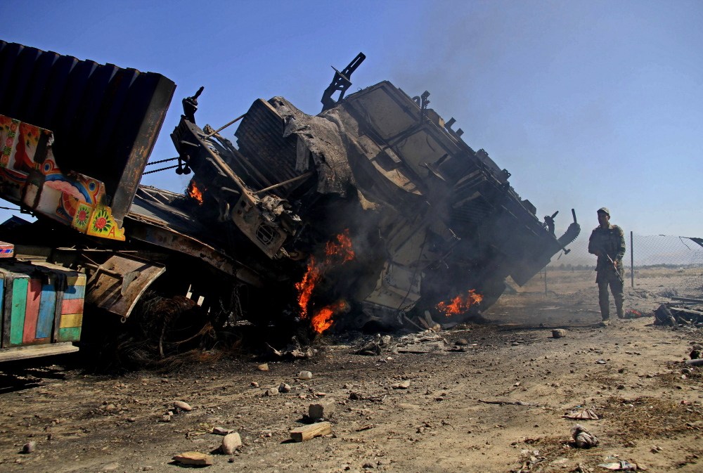 The Associated Press An Afghan policeman stands near a burning NATO supply truck in Behsud district of Jalalabad east of Kabul, Afghanistan, Monday. An Afghan provincial official says suicide bombers attacked a parking lot at a police base in eastern Afghanistan, killing a guard and setting almost two dozen trucks ablaze.