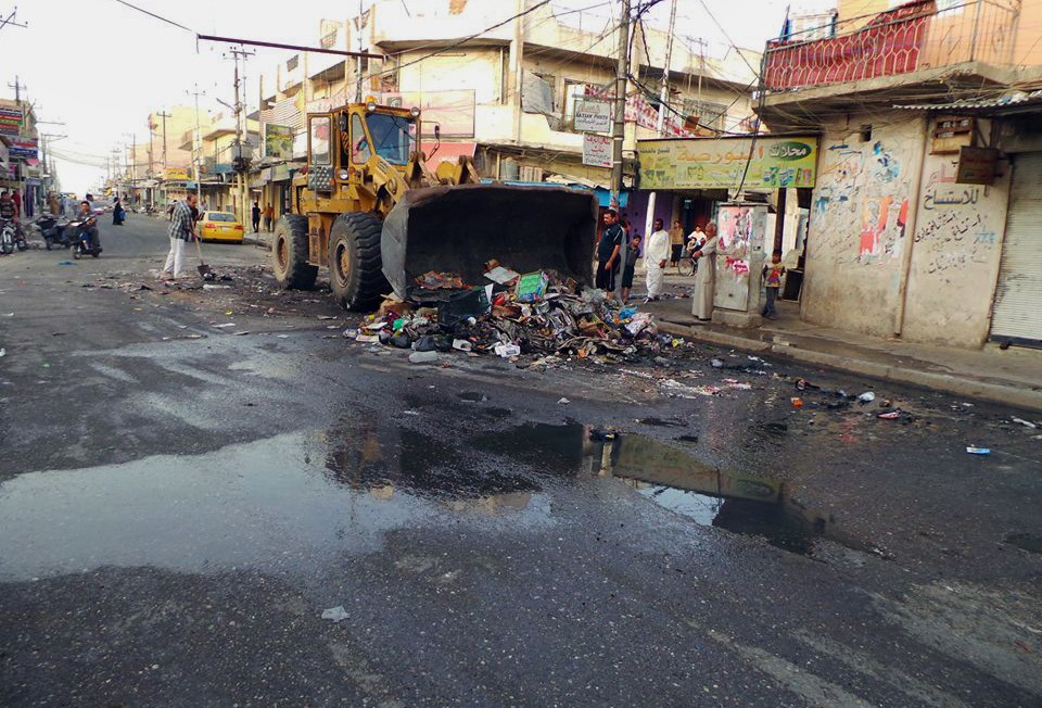 A municipality bulldozer and people clean a street in the northern city of Mosul, Iraq, Friday. Iraqi officials say al-Qaida-inspired militants who this week seized much of the country’s Sunni heartland have pushed into an ethnically mixed province northeast of Baghdad, capturing two towns there.