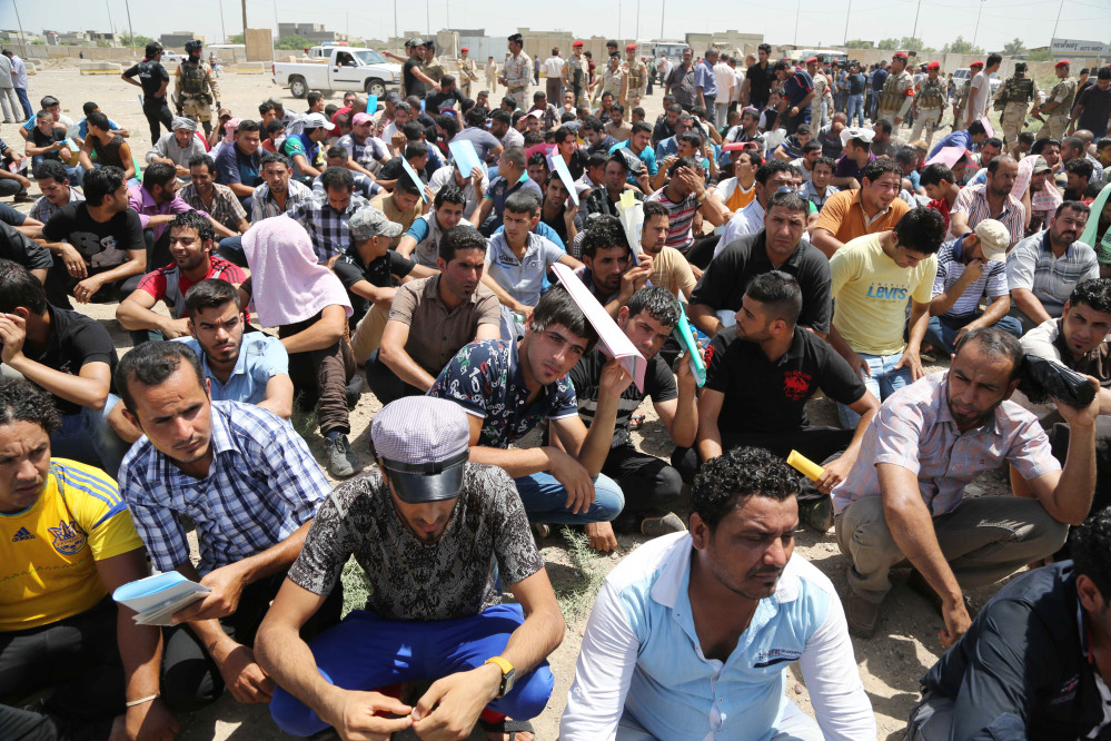 Iraqi men gather outside of the main army recruiting center to volunteer for military service in Baghdad, Iraq on Saturday after authorities urged Iraqis to help battle insurgents.