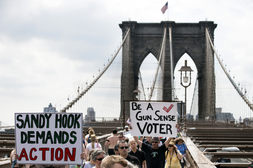 Demonstrators raise posters as they march across the Brooklyn Bridge to call for tougher gun control laws on Saturday in New York. The protest was underwritten by former New York Mayor Michael Bloomberg, one of the most visible gun control advocates in the U.S., and included relatives of some of those slain in the 2012 shooting rampage at Sandy Hook Elementary School in Newtown, Conn.