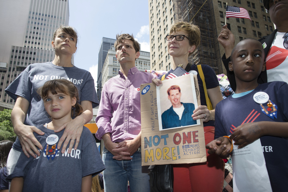 Actress Amanda Peet, left, holds her daughter alongside fellow actor Adam Scott, center, and relatives of gun violence victims at a rally outside city hall to call for tougher gun control laws on Saturday in New York.