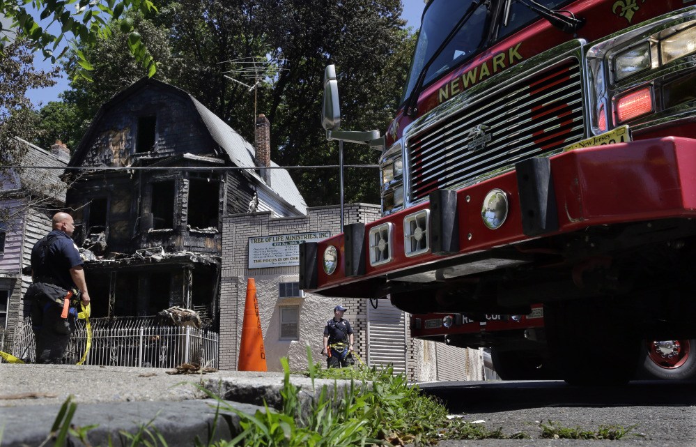 Firefighters and police work near the rubble of a burned out home as they look for clues to a fire that authorities say killed six people in Newark, N.J., Sunday.