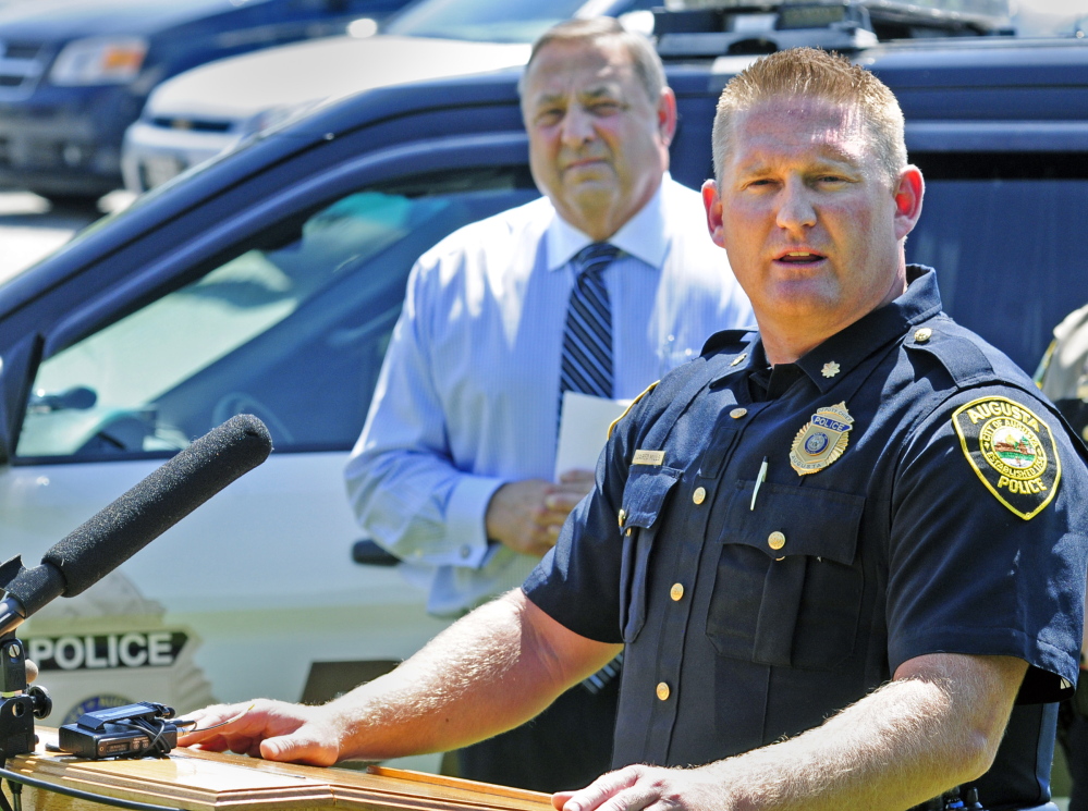 Gov. Paul LePage, left, listens as Augusta Deputy Chief Jared Mills talks during a news conference held to announce that crime in Maine decreased 9.1 percent in 2013.