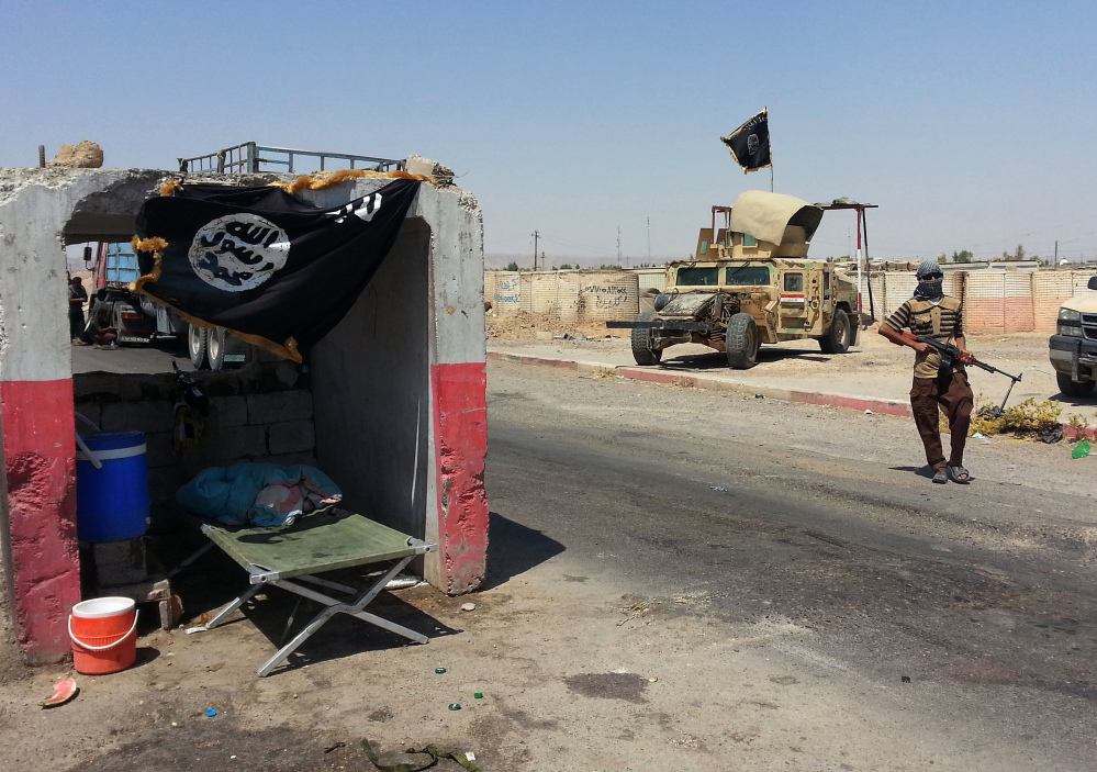 An al-Qaida-inspired militant stands with a captured Iraqi Army Humvee at a checkpoint outside Beiji refinery, some 155 miles north of Baghdad, Iraq, on Thursday.