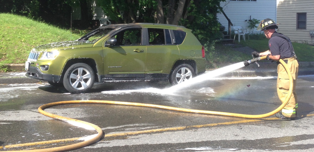 Winslow Fire Lt. Scott Higgins hoses down an SUV that caught fire in Waterville Monday. The driver and his sons escaped injury.