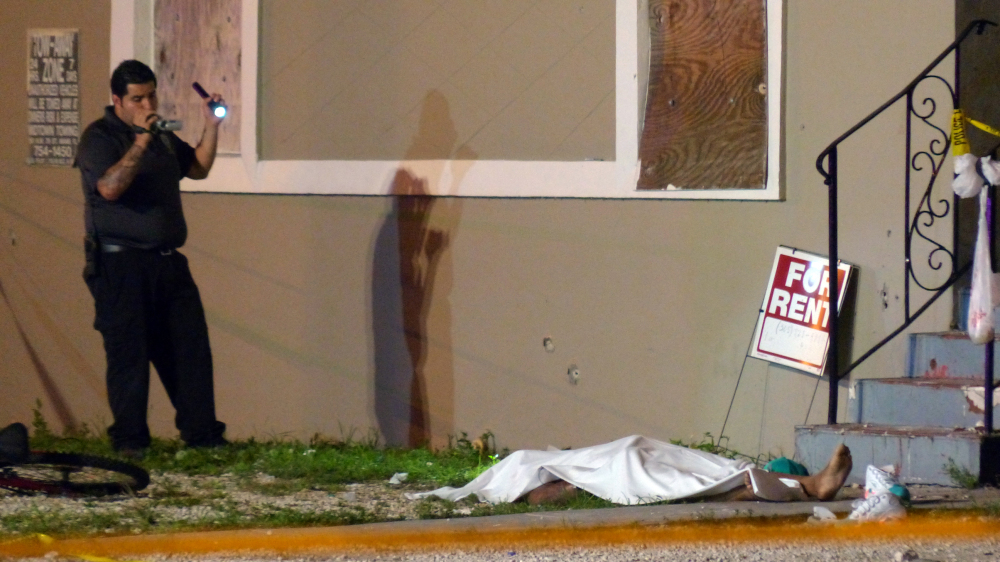 An investigator films an area of a scene where at least two people were killed and multiple others wounded following a shooting early Tuesday in Miami’s Liberty City neighborhood.