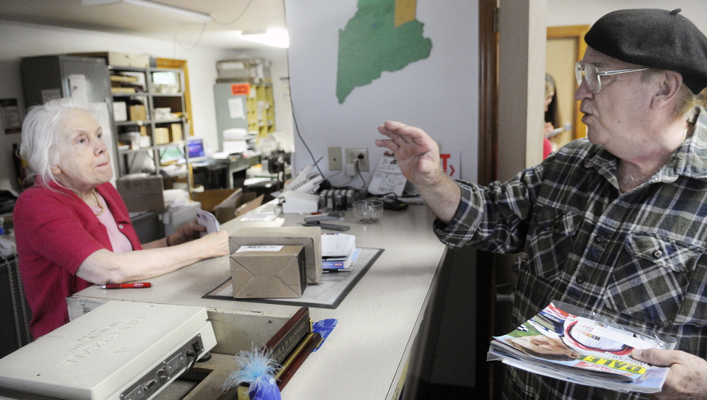 Mel Mounts confers with Postmaster Sheila Sanford Wednesday at the post office in North Monmouth. Mounts said he’s not concerned about reduced hours because he’s retired, but understands it could be a problem for those who work.
