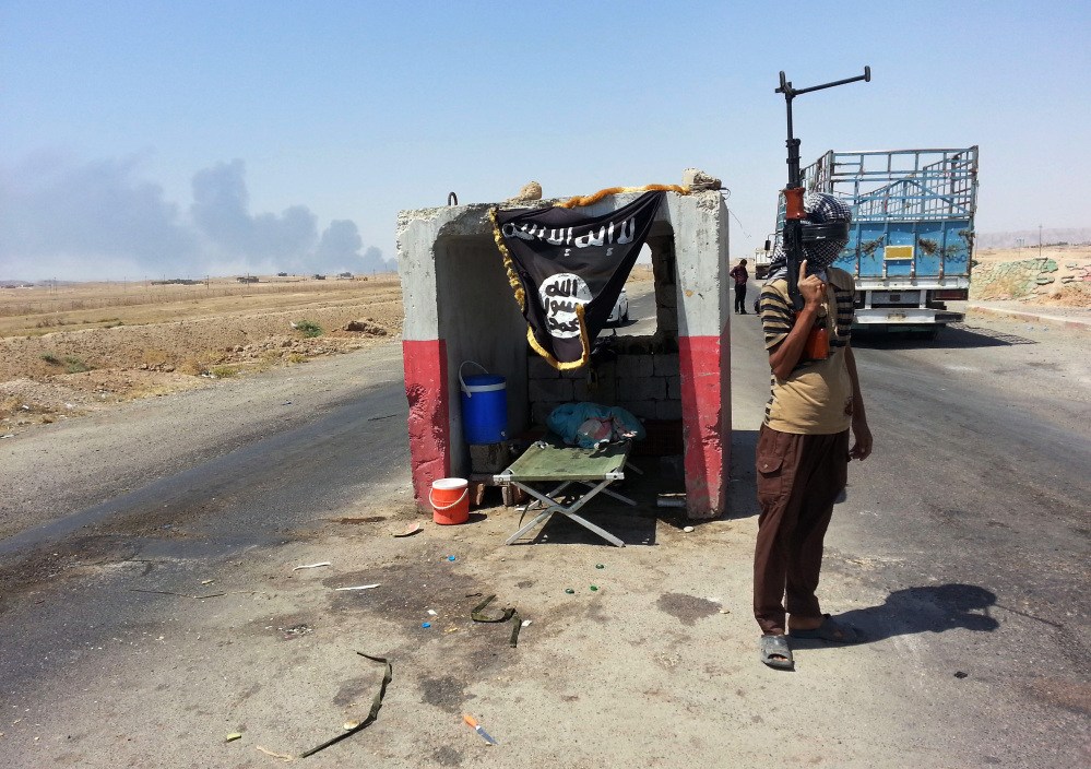 An al-Qaida-inspired militant stands guard recently at a checkpoint captured from the Iraqi Army outside Beiji refinery, some 155 miles north of Baghdad. The Sunni militant offensive has prompted Shiite militias to reconstitute themselves, deepening fears of a return to the sectarian bloodletting that pushed Iraq to the brink of civil war in 2006 and 2007.