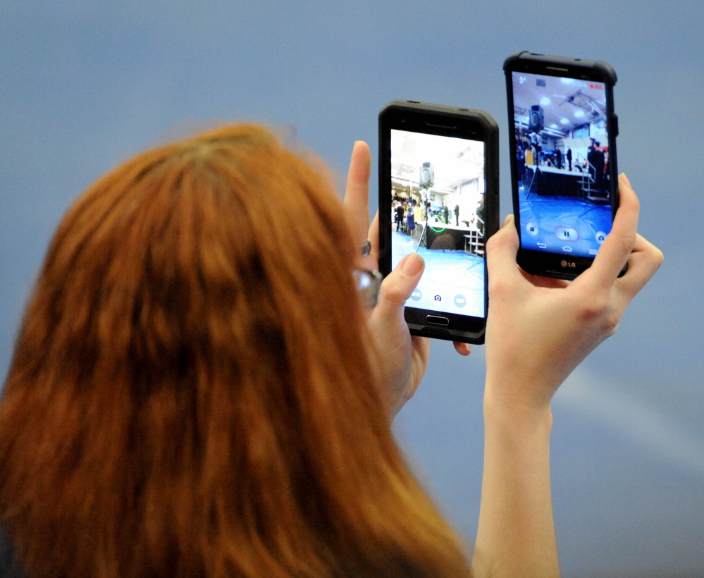 Staff photo by Michael G. Seamans 
 A woman takes double duty with two camera phones during commencment ceremonies at the Alfond Athletic Center at Colby College in Waterville on Wendesday, June 3, 2014.
