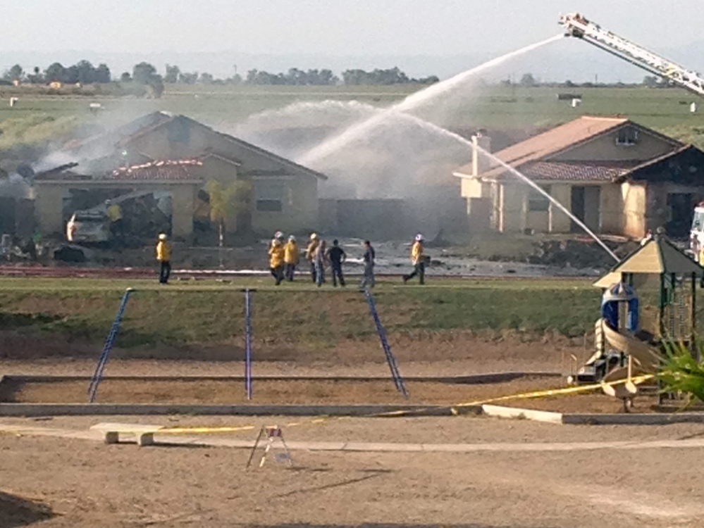 This photo provided by Isaac Ramos shows firefighters putting out a fire caused when a military jet crashed in residential neighborhood in Imperial, Calif., Wednesday, June 4, 2014. Witnesses say two houses caught fire after the crash. (AP Photo/Issac Ramos)