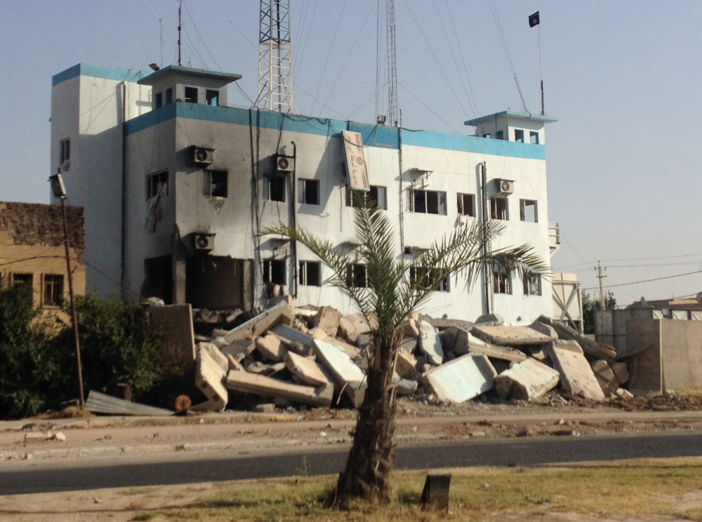 A black flag used by the al-Qaida inspired lslamic State of Iraq and the Levant waves from a damaged police station in the northern city of Mosul, Iraq, Tuesday. The militant extremist group’s unilateral declaration of an Islamic state is threatening to undermine its already-tenuous alliance with other Sunnis who helped it overrun much of northern and western Iraq.