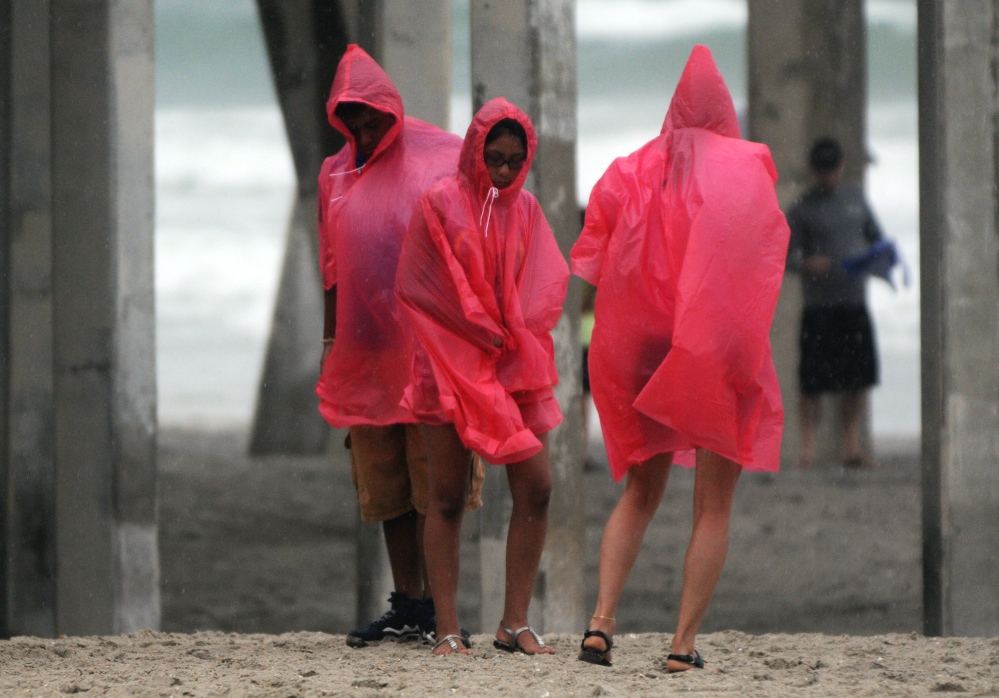 Beachgoers huddle on the beach at Wrightsville Beach, N.C., on Thursday. Residents along the coast of North Carolina are bracing for the arrival of the Hurricane Arthur, a Category 1 storm.