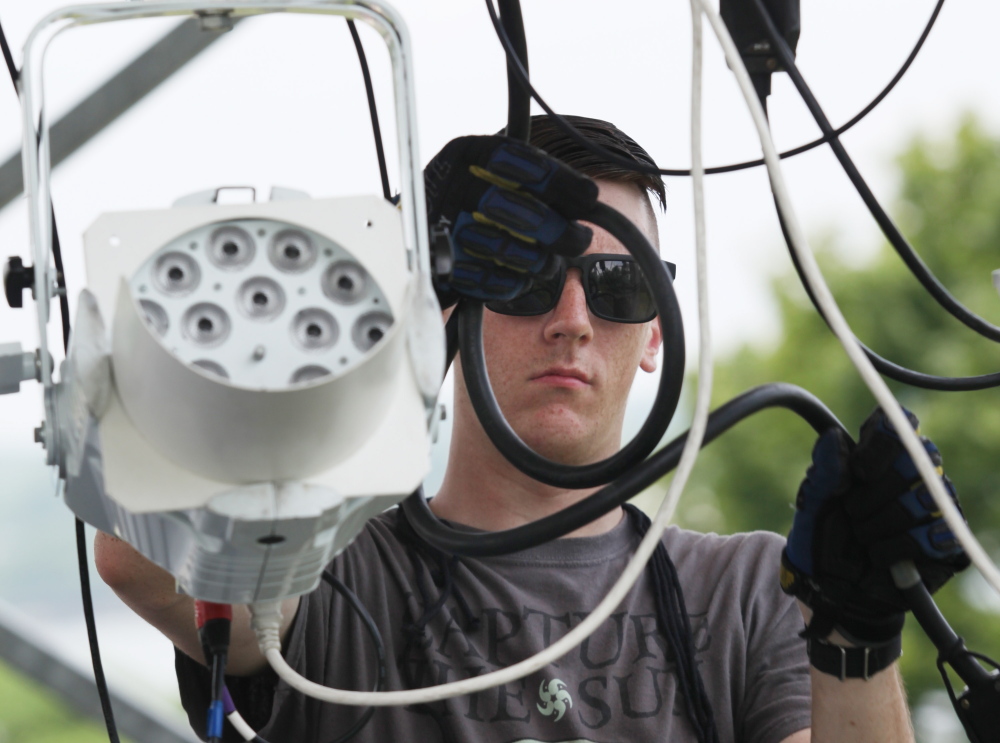 Kyle Hussey works on the stage lights Thursday, a day before stormy weather is expected. The National Weather Service projected mostly clear conditions for Saturday night.