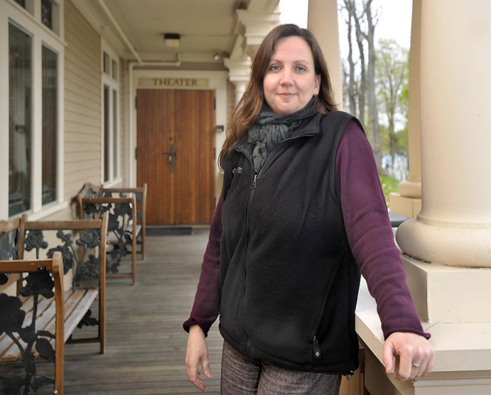 Dawn McAndrews, the producing artistic director at the Theater at Monmouth stands on the veranda entrance to the theater, graced with large columns.