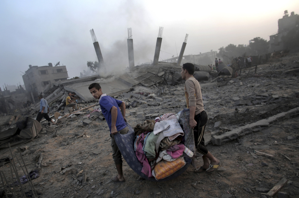 Palestinians try to salvage what they can of their belongings from the rubble of a house destroyed by an overnight Israeli airstrike in Gaza City Tuesday.