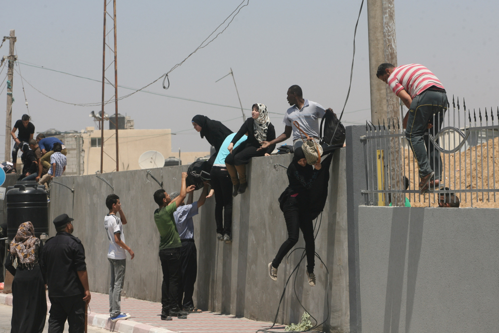 Palestinians climb a wall over as they try to cross into Egypt at the border between the Gaza Strip and Egypt in Rafah on Thursday. Egyptian authorities opened the border to let wounded Palestinians cross for medical treatment in Egyptian hospitals.