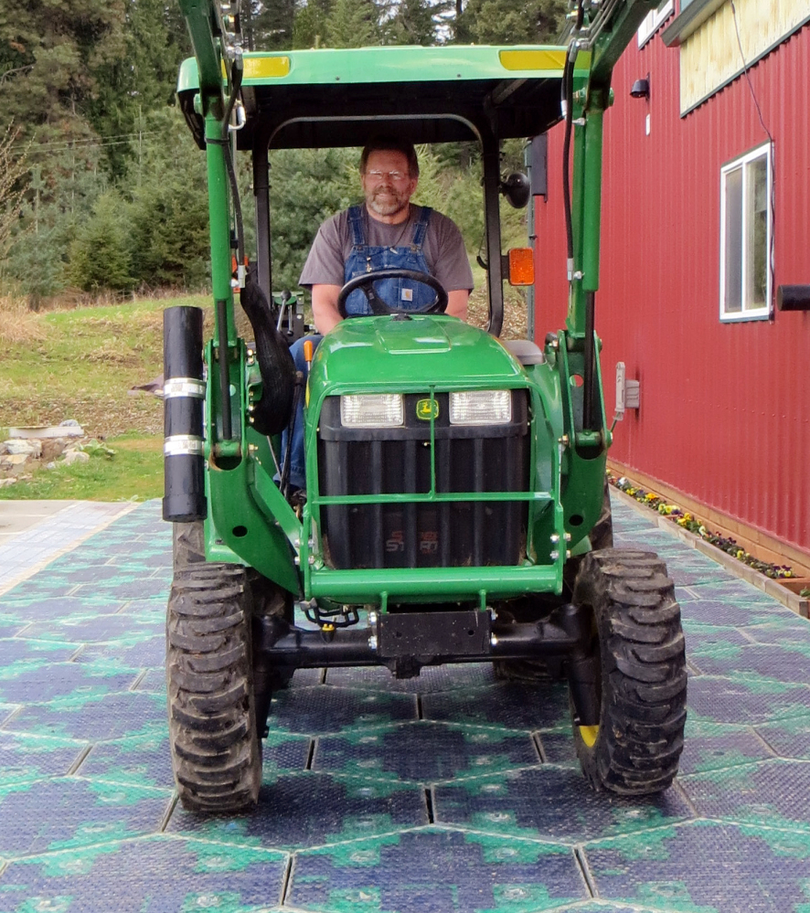Scott Brusaw drives a tractor on a prototype solar-panel parking area at his company’s headquarters in Sandpoint, Idaho. Skeptics wonder about the durability of the panels, which are covered by knobby, tempered glass.