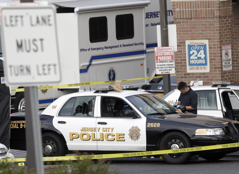 A Jersey City Police Department cruiser is seen with its back window shattered as officials investigate the scene where a Jersey City Police Department officer was shot and killed while responding to a call at a 24-hour pharmacy on Sunday.