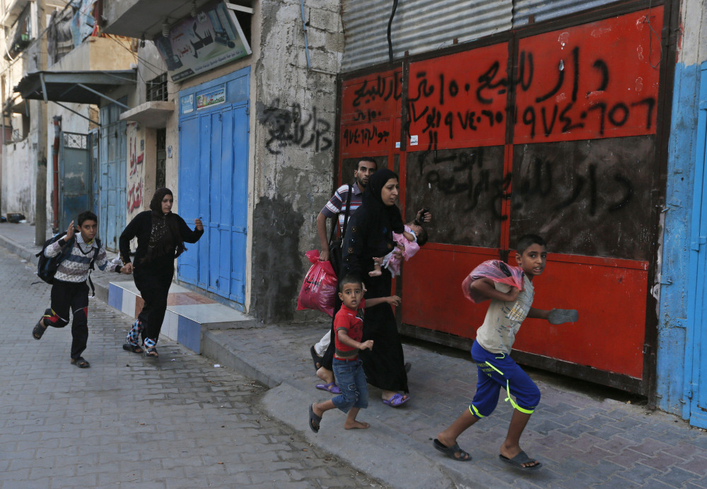 Palestinians run for shelter as they hear bombing in the distance while they flee their homes in the Shajaiyeh neighborhood of Gaza City, after Israel had airdropped leaflets warning people to leave the area, on Wednesday.