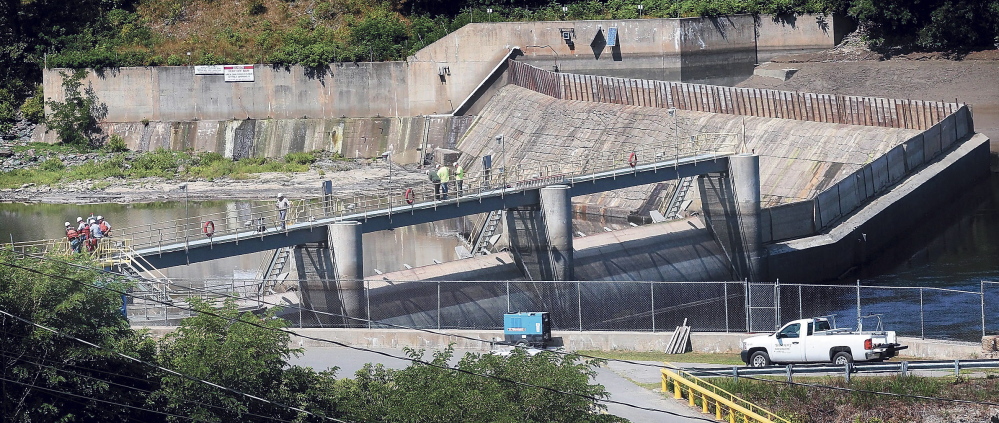 Workers stand atop the Brookfield Dam that spans the Kennebec River between Winslow and Waterville in this file photo. The dam is one of four owned by Brookfield that are the subject of a lawsuit by environmenal groups seaking to protect Atlantic salmon. A federal appeals court Monday revived part of the suit that was dismissed last year.