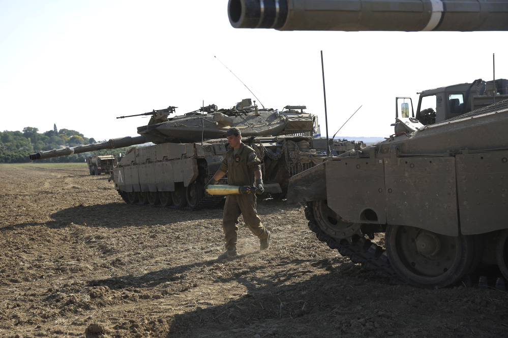 An Israeli soldier carries a tank shell near the border of Israel and the Gaza Strip, Sunday.