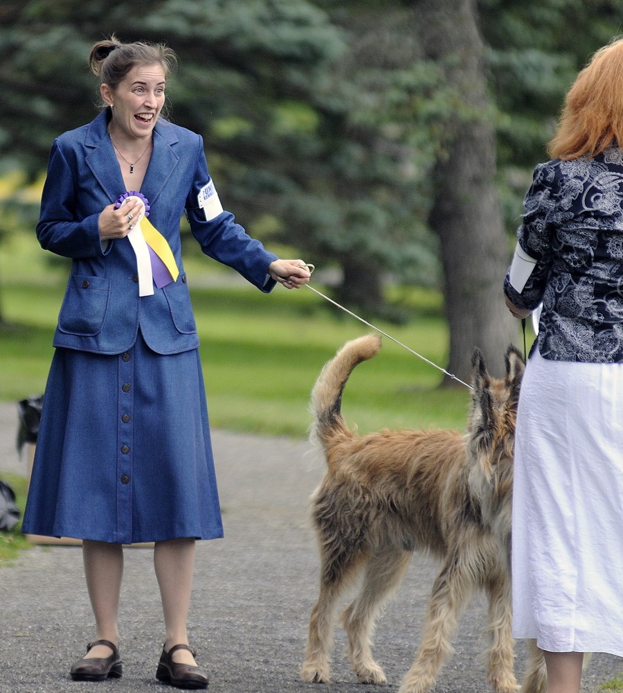 Celestia Lensky, of New Hampshires, clutches ribbons she collected for showing her dog Sunday during the UKC Acadia Belgian Shepherd Dog Club dog show at Capitol Park in Augusta.