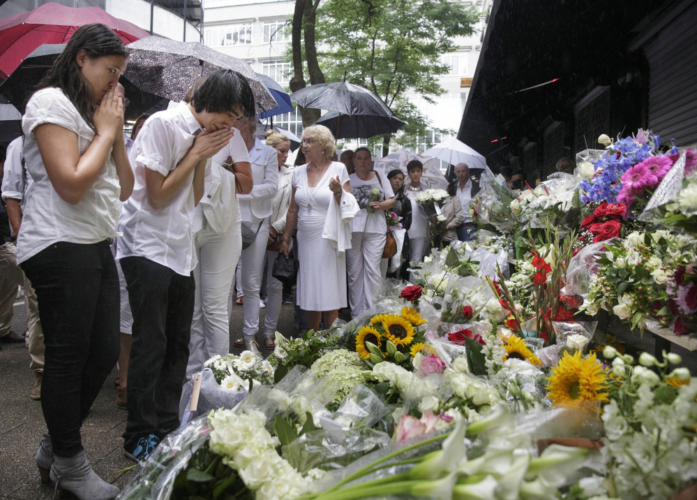 People react as they look at flowers placed in front of the Asian Glories restaurant, after a walk to commemorate victims of Flight 17 in Rotterdam on Monday.
